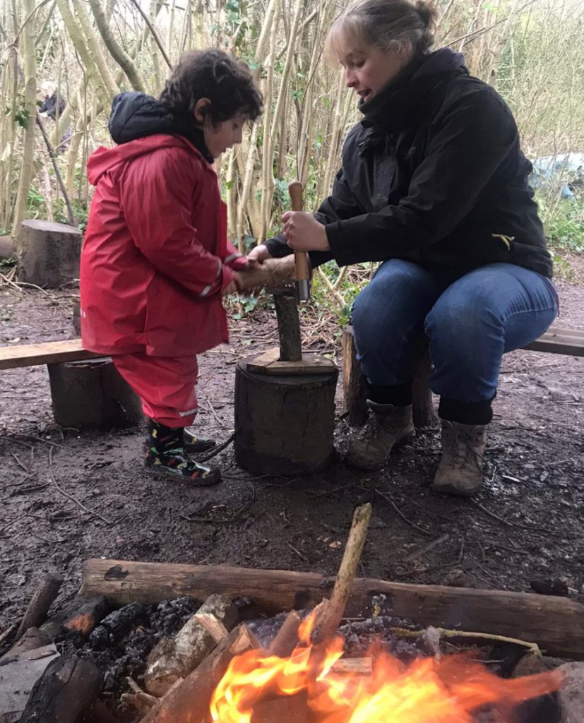 Young child learning how to split wood with a froe